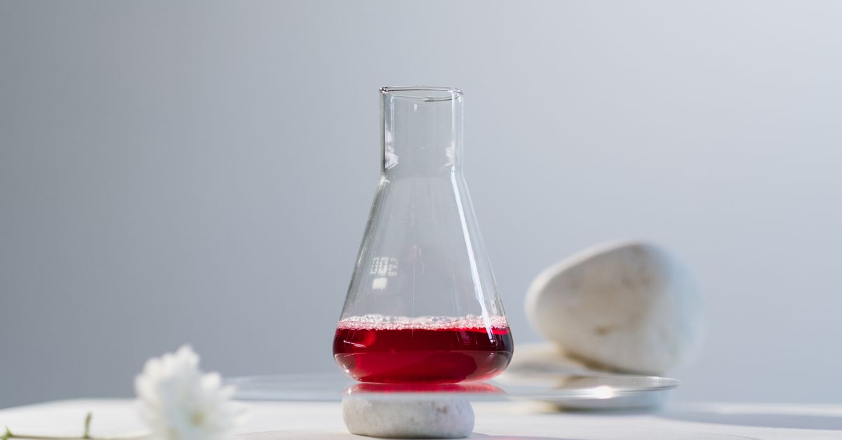 A minimalist setup featuring a flask with red liquid in a science lab setting.