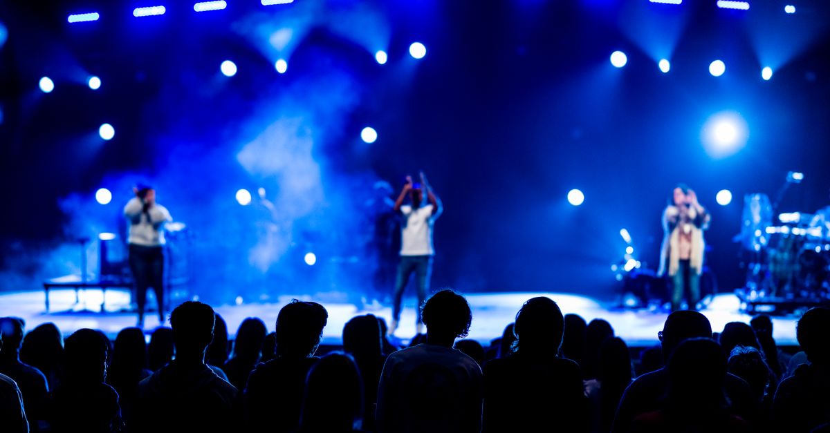 Vibrant live concert scene with audience silhouettes, stage performers, and dynamic lighting.