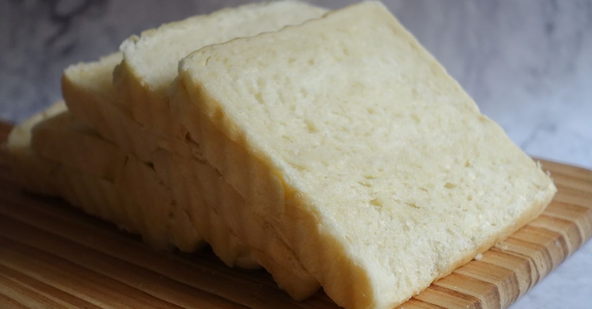 Close-up of freshly sliced white bread arranged on a wooden chopping board, perfect for culinary presentations.