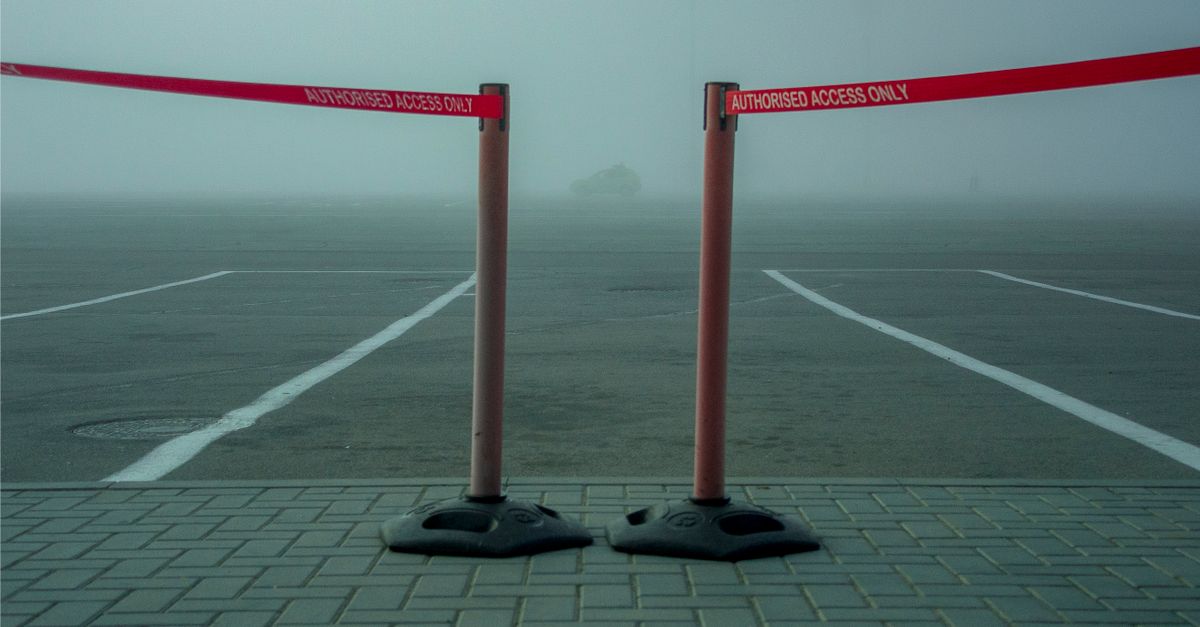 A foggy parking lot featuring a retractable barrier tape labeled 'AUTHORIZED ACCESS ONLY.'