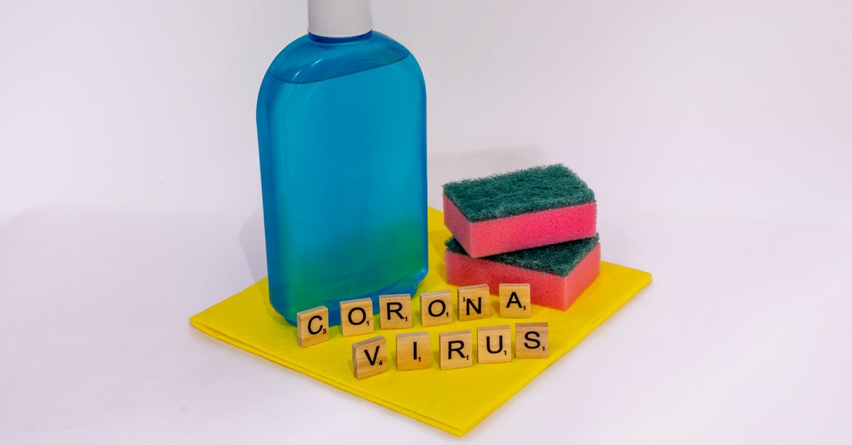 Cleaning products with scrabble tiles spelling 'coronavirus' on a white surface.