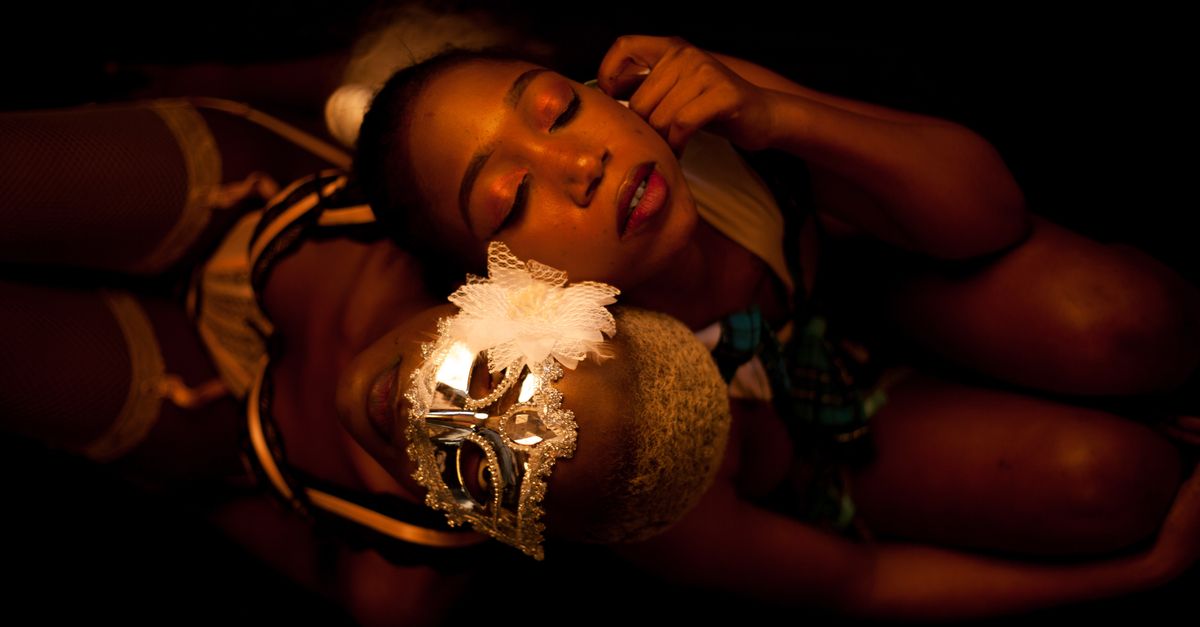 A captivating overhead shot of two women posing with a decorative mask.