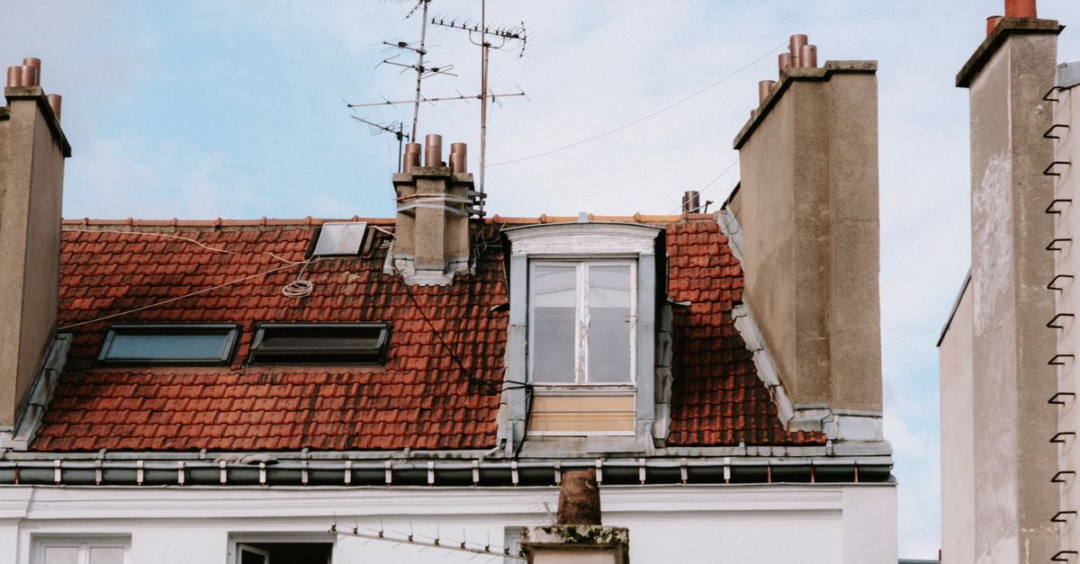A quaint urban rooftop with chimney and antennas, capturing architectural details and city vibe.