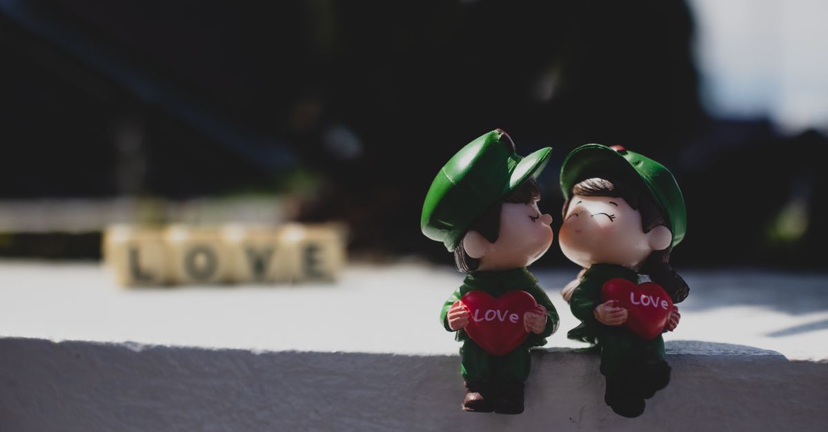 Close-up of two soldier-themed figurines holding love hearts in a romantic setting.