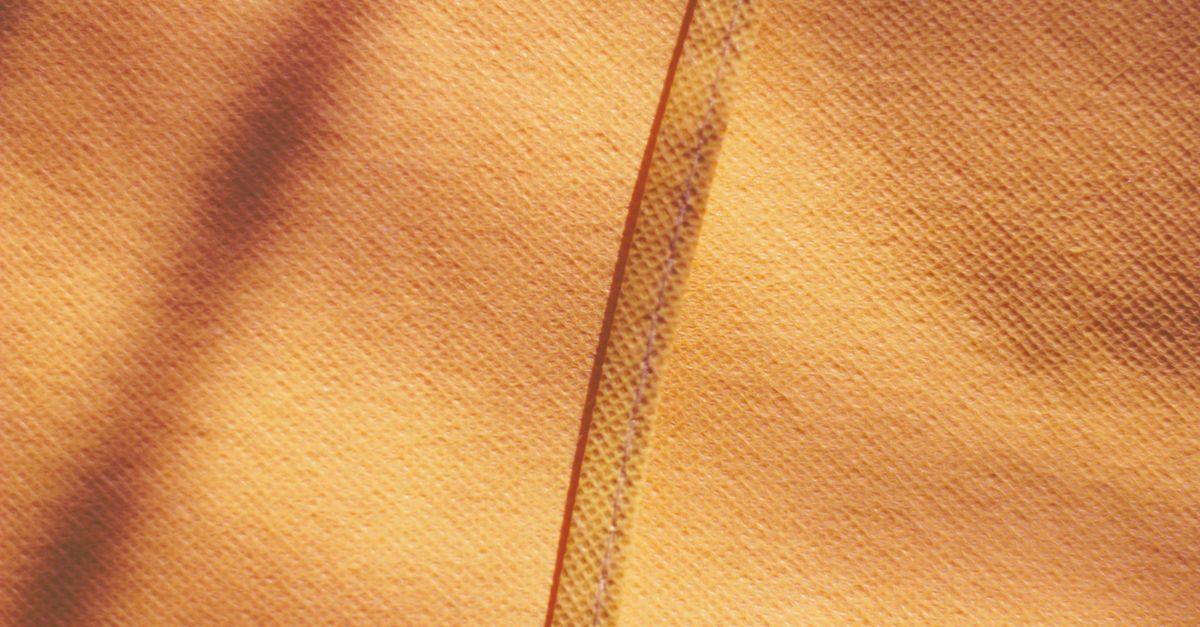 Close-up of yellow fabric showcasing texture with a shadow and stripe detail.