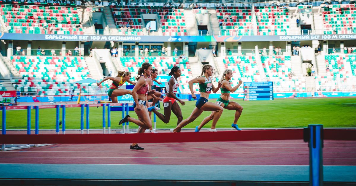 Athletes compete in an intense women's hurdles event at Minsk stadium, showcasing speed and agility.