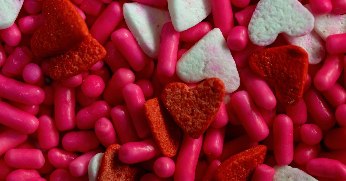 A vibrant assortment of red and pink heart-shaped and cylindrical candies.