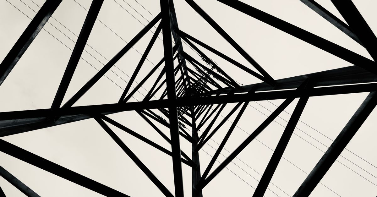 Black and white low angle shot of a transmission tower showcasing geometric patterns.