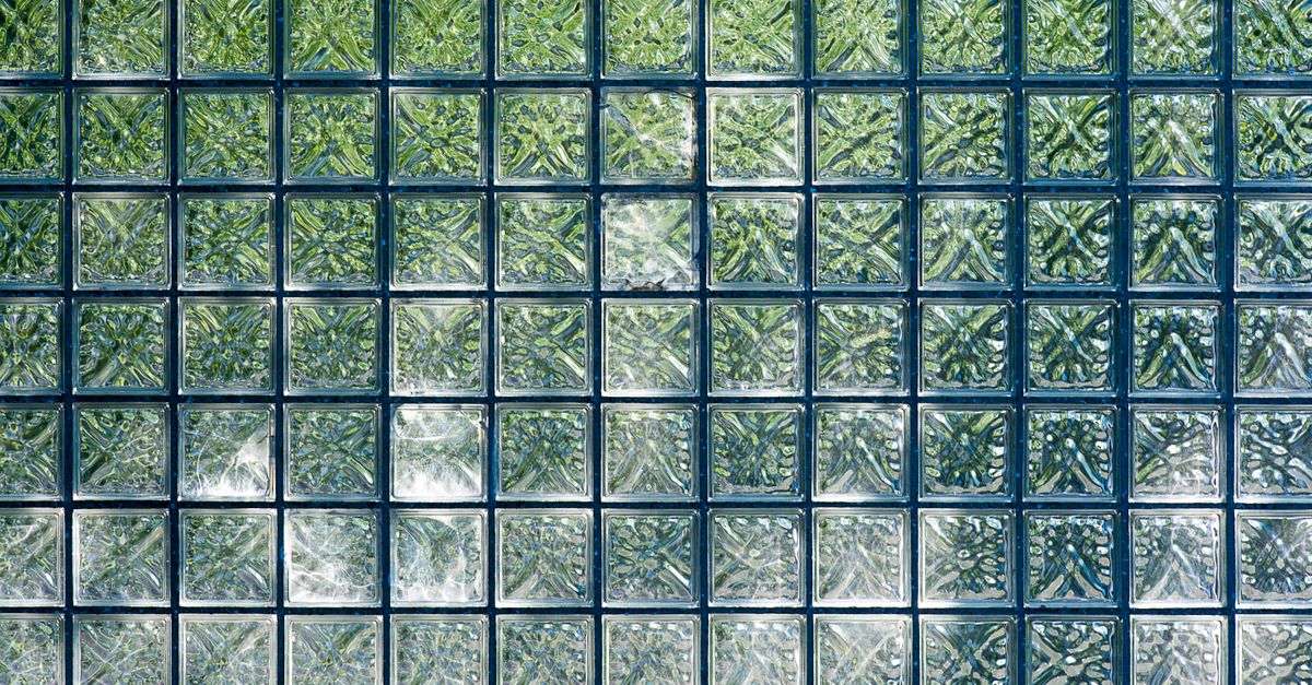 Close-up of square glass blocks creating a textured, geometric pattern in green hues.
