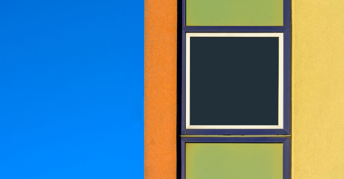Vibrant modern architecture with geometric windows and colorful walls against a clear blue sky.