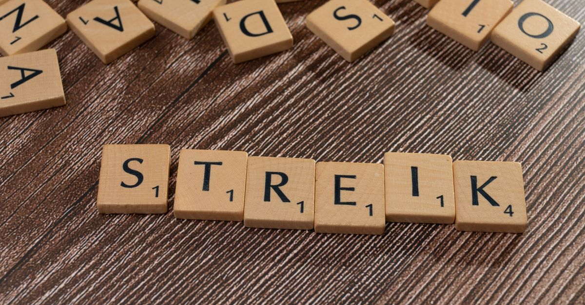 Wooden letter tiles spelling 'Streik' on a textured wooden surface, top view.