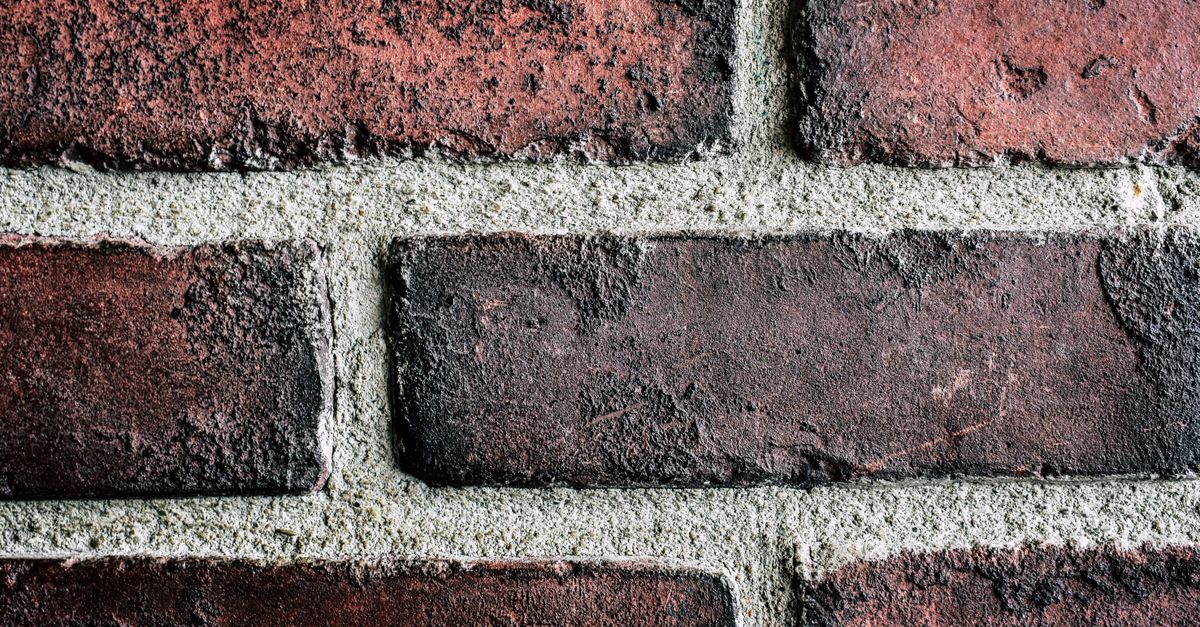 Detailed close-up of a textured red brick wall with visible mortar lines, emphasizing texture and structure.