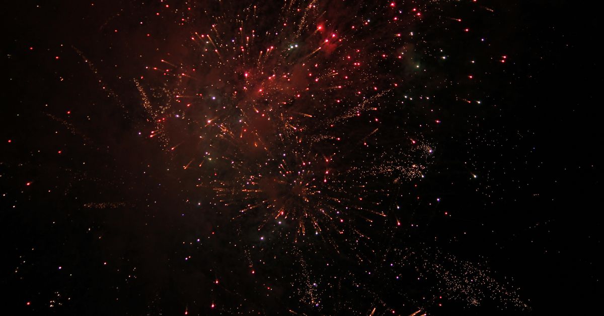 Vibrant fireworks illuminating the dark sky with bursts of red and white light.