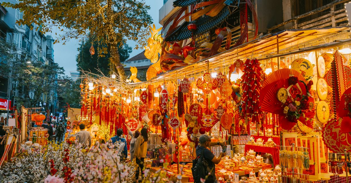 A bustling Vietnamese street market with Tet holiday decorations and colorful ornaments.