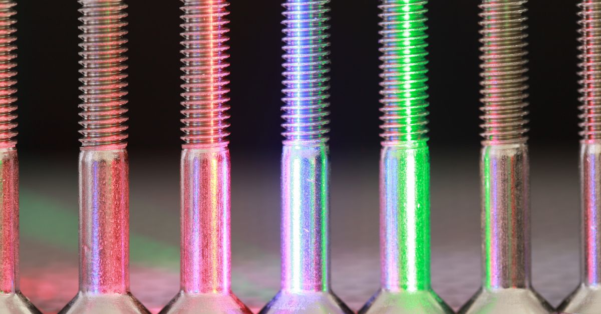 Vibrant close-up of metallic bolts featuring multicolored neon lighting effect.