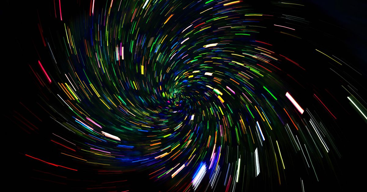 Dynamic spiral of colorful light trails on a dark background, captured with long exposure.
