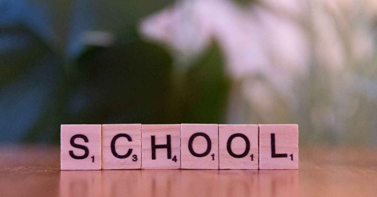 Wooden tiles spelling the word school on a table, evoking educational themes.
