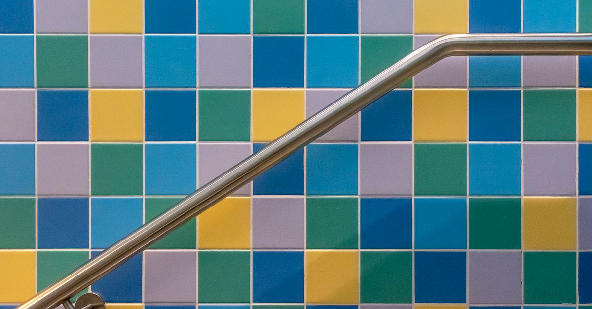 Vibrant square tiles in blue, yellow, and green with a sleek stainless steel railing.