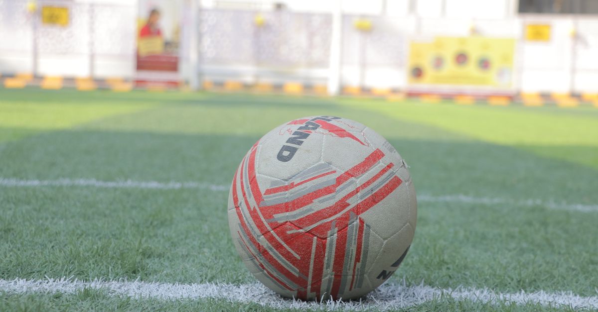 Close-up of a soccer ball on a green field with white lines, ready for play.