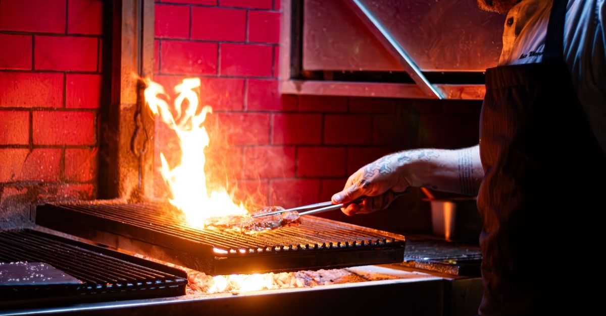 A chef grills meat over an open flame, showcasing vibrant cooking in Thành phố Hồ Chí Minh's lively cuisine scene.