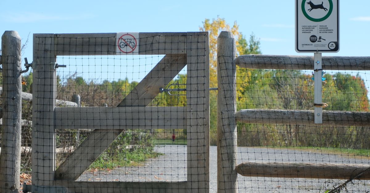 Rustic wooden gate with no cycling sign, scenic park background in autumn.