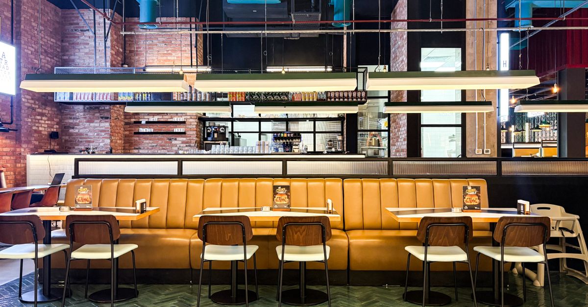 Contemporary restaurant interior with brown leather seating, stylish lighting, and open kitchen view.