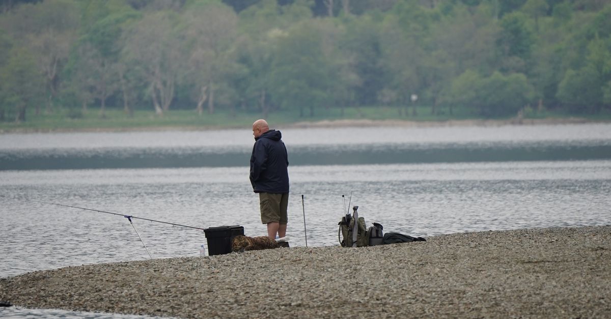 Tranquil scene of a man fishing by a Scottish lake, perfect for a relaxing getaway.