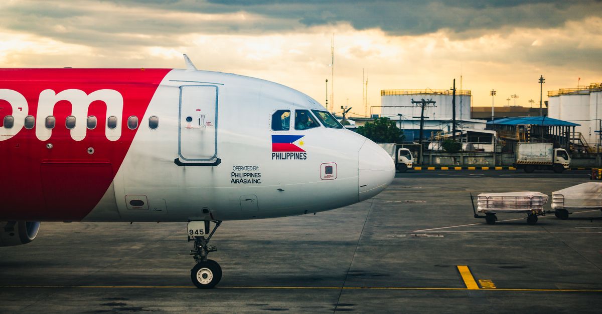 AirAsia airplane parked on a tarmac at a Philippine airport with cloudy skies.