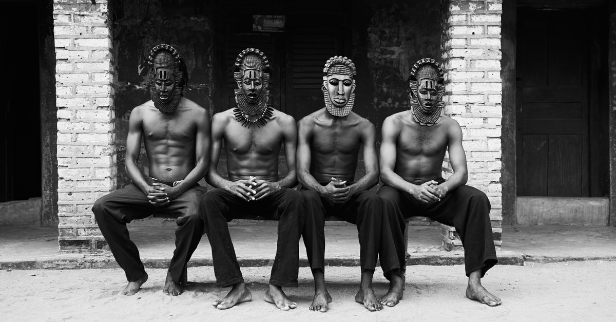 Four men with traditional masks sit in unity, showcasing cultural heritage.
