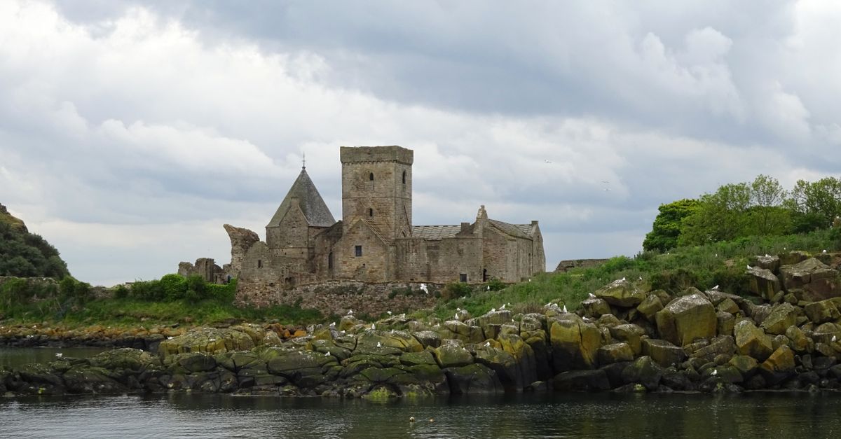 Explore the captivating ruins of Inchcolm Abbey set against a serene coastal backdrop in Scotland.