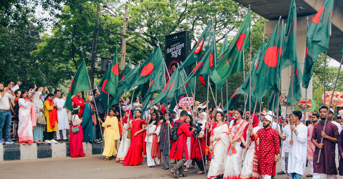 Vibrant Pohela Boishakh parade in Dhaka, showcasing colorful traditional attire and flags.