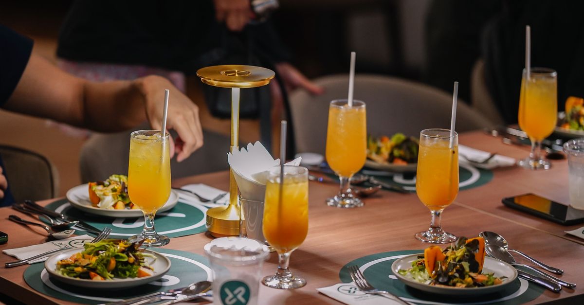 A lively table setup with refreshing orange beverages, salad dishes, and elegant decor in a cozy indoor setting.