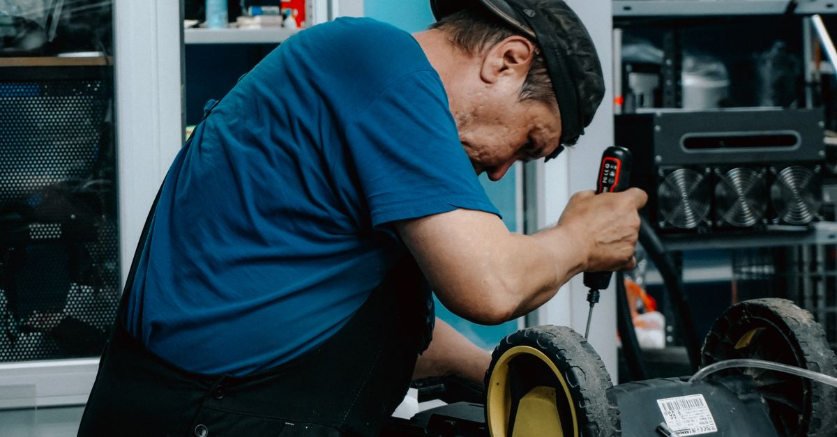Focused adult male is repairing an electric toy vehicle in a workshop setting.