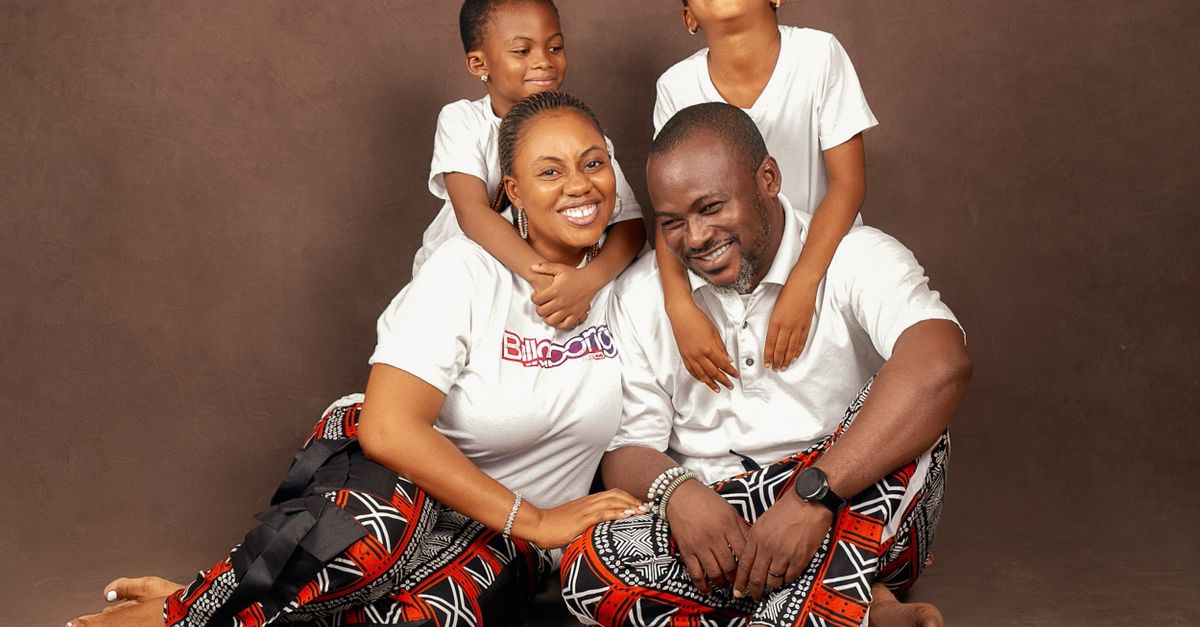 Joyful African family portrait with parents and children wearing traditional attire indoors.