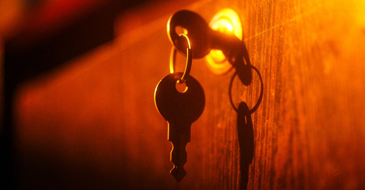 A close-up of a key in a lock with dramatic lighting and shadow play on a warm-toned wooden surface.