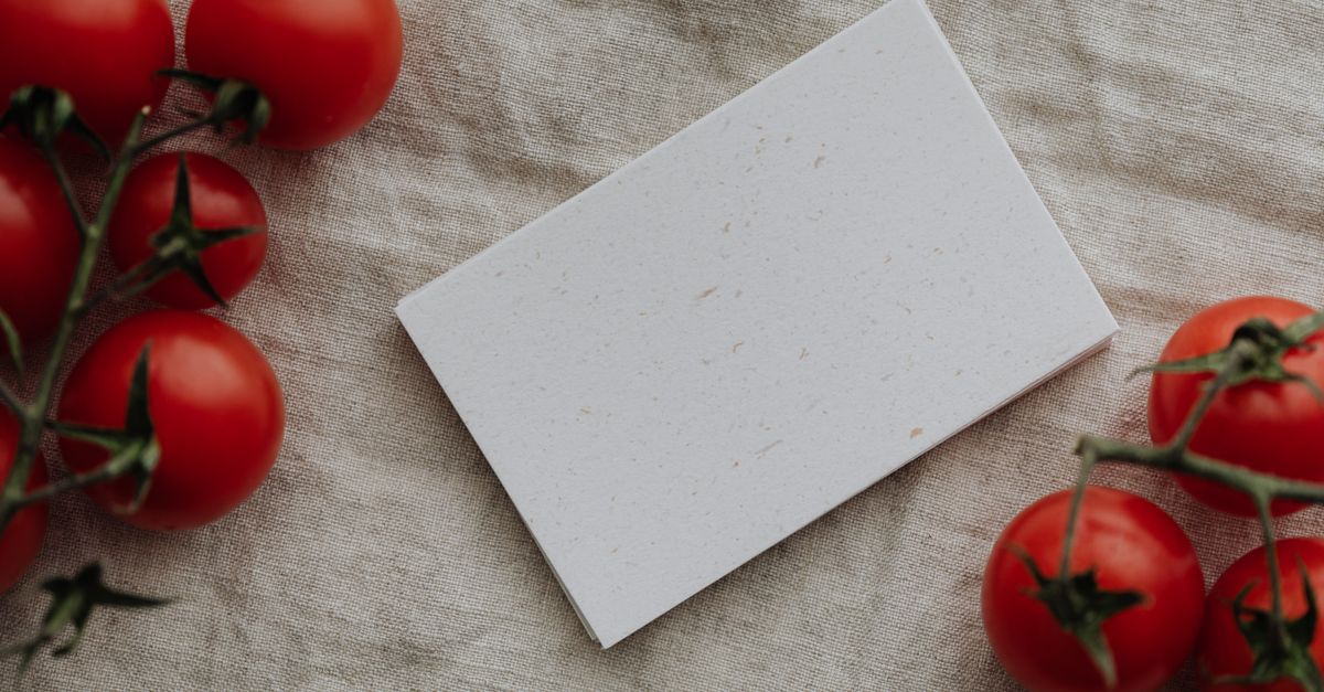 Rustic flat lay featuring fresh cherry tomatoes and a blank card on linen fabric. Perfect for creative mockups.