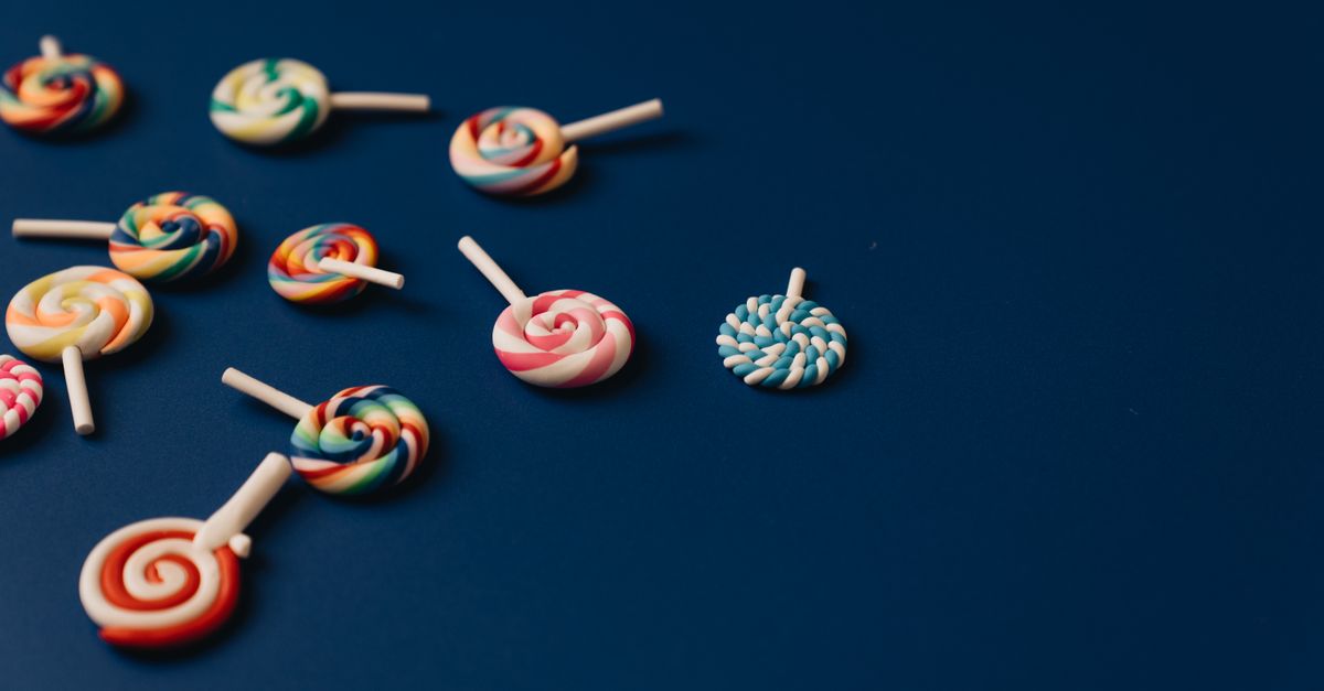Brightly colored lollipops scattered on a blue background, offering ample copy space.