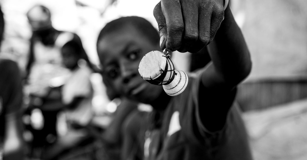 Captivating black and white portrait of a young boy holding a handmade item, shot in Accra, Ghana.