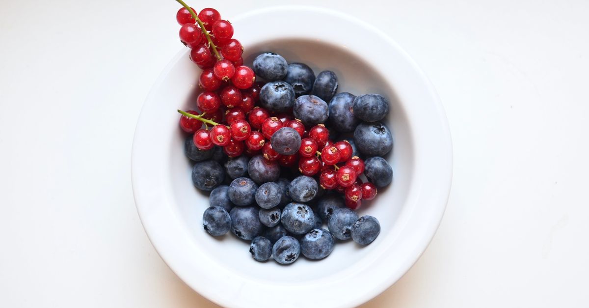 From above of appetizing blueberry and red currant in bowl on white table