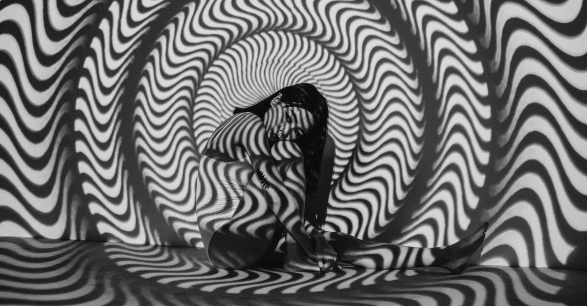 A woman enveloped in a trippy black and white optical illusion, creating a striking visual effect.