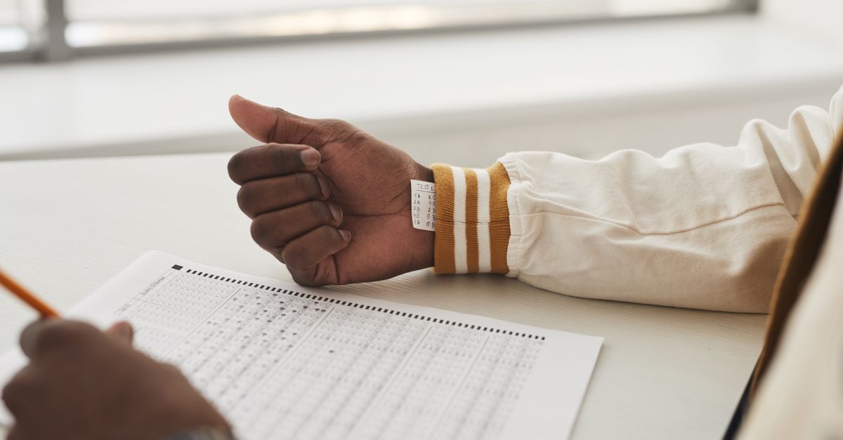 Close-up of a student cheating in an exam by hiding notes under a sleeve during a test.