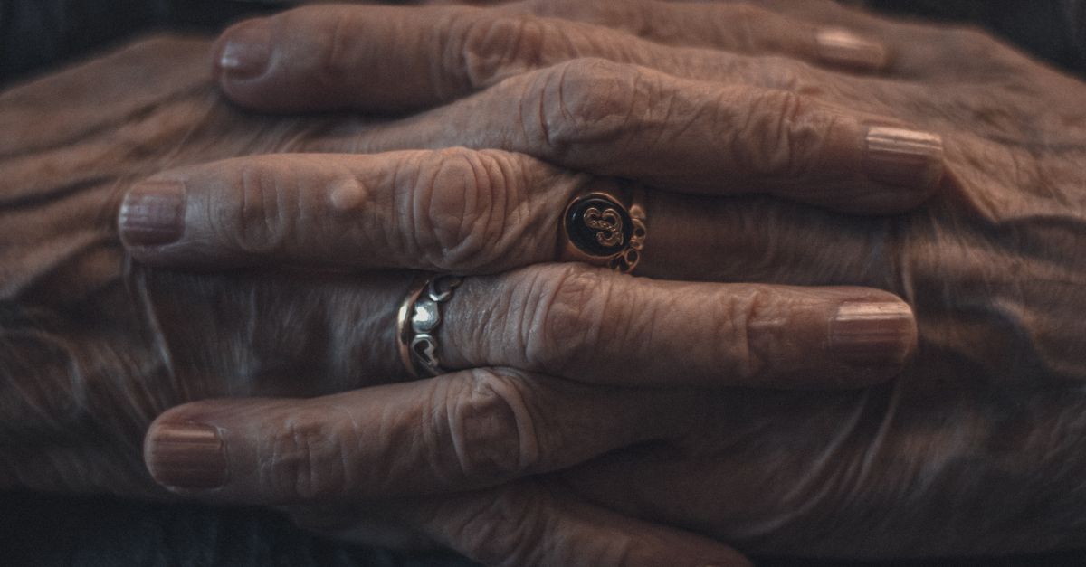 Intimate close-up of elderly hands adorned with rings, showcasing wrinkles and age.