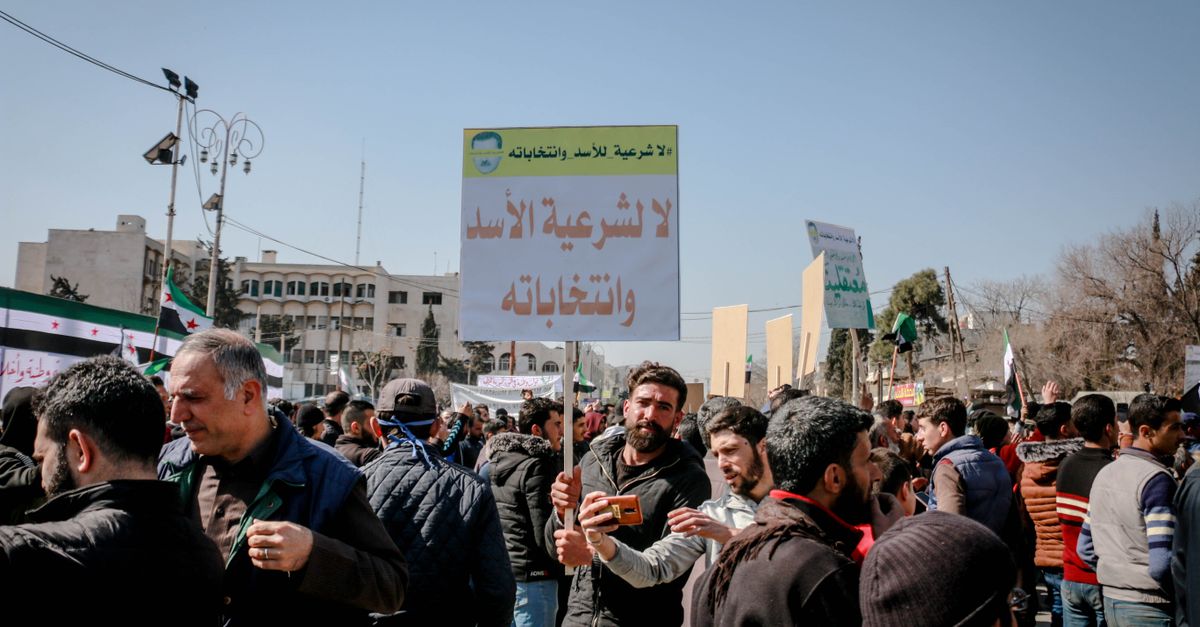 Unrecognizable Arab male activists with inscriptions on placards during strike in town under light sky