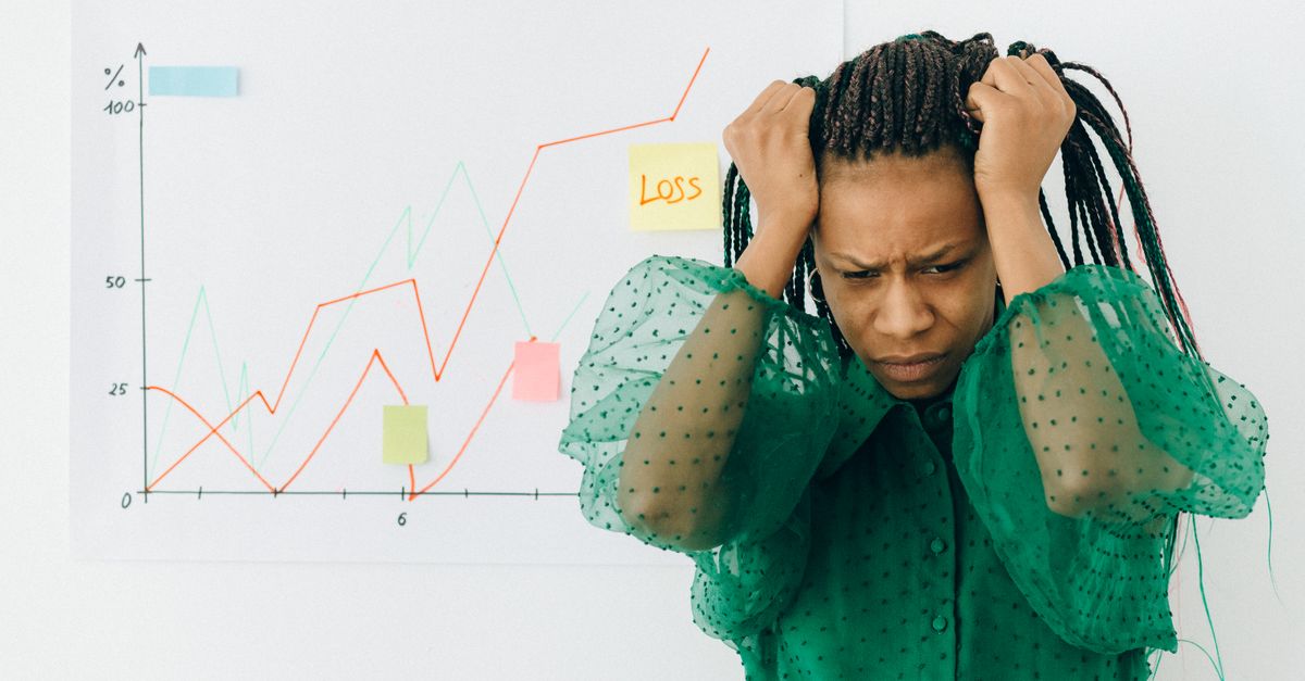 Frustrated businesswoman in green blouse analyzing a graph showing financial loss.