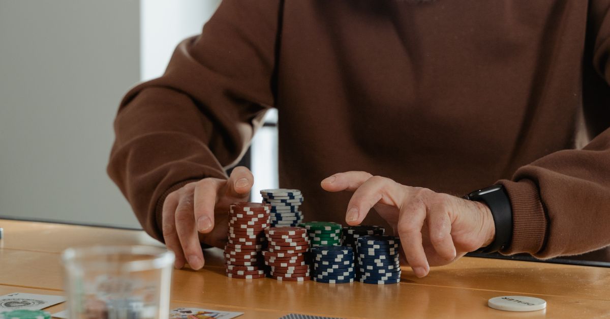 Close-up of an elderly man arranging poker chips during a game indoors.