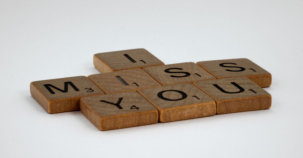 Close-up of Scrabble tiles spelling 'I Miss You' on a white surface with ample copy space.