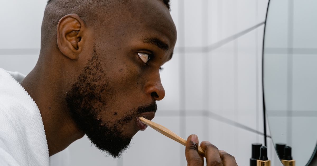 Close-up of a man brushing his teeth in front of a bathroom mirror, focusing on hygiene and self-care.