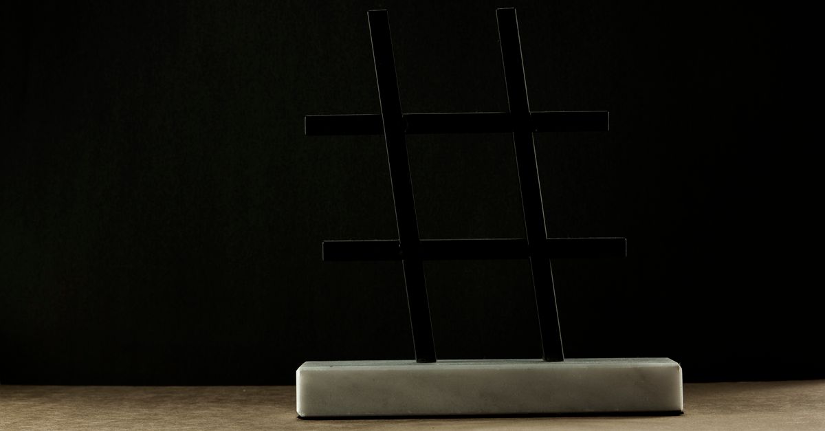 A modern hashtag sculpture in a minimalist setting with a dark backdrop.