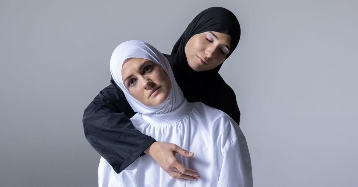 Emotional studio portrait of two women wearing hijabs, showcasing unity and friendship.