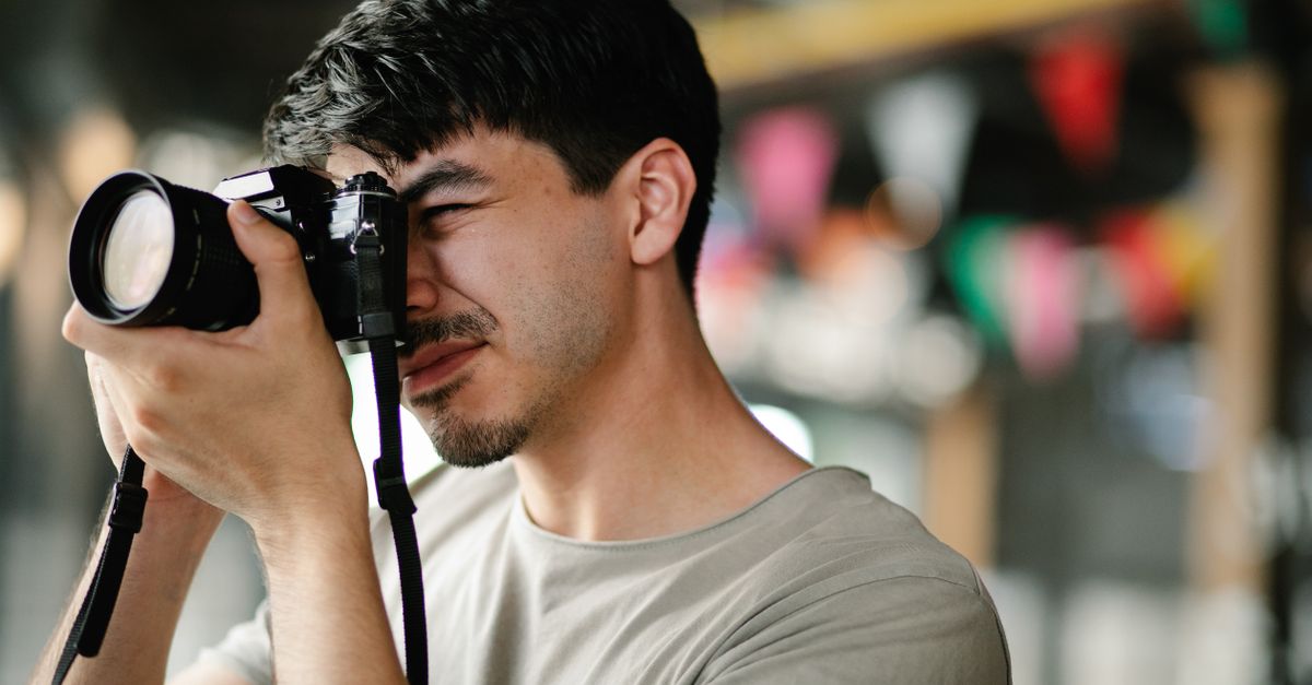 Focused photographer using a DSLR camera, capturing candid moments indoors.